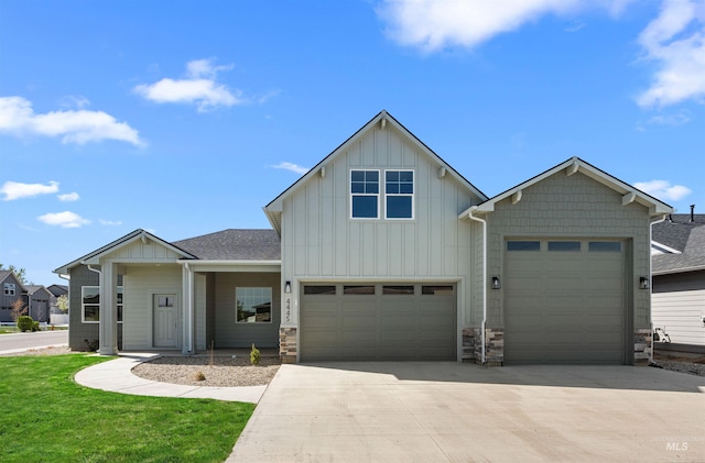 view of front of property with board and batten siding, roof with shingles, a garage, concrete driveway, and stone siding