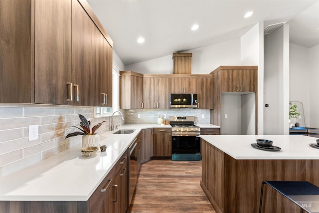kitchen featuring light countertops, appliances with stainless steel finishes, a sink, and vaulted ceiling