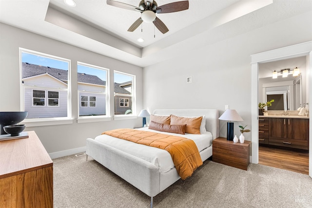 carpeted bedroom with a sink, a raised ceiling, baseboards, connected bathroom, and recessed lighting