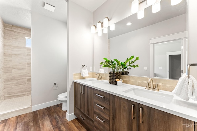 full bath featuring a sink, double vanity, toilet, and tiled shower