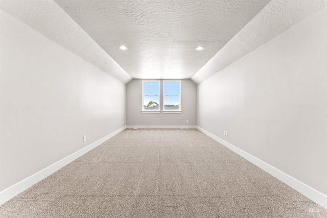 additional living space with baseboards, light colored carpet, a textured ceiling, and lofted ceiling
