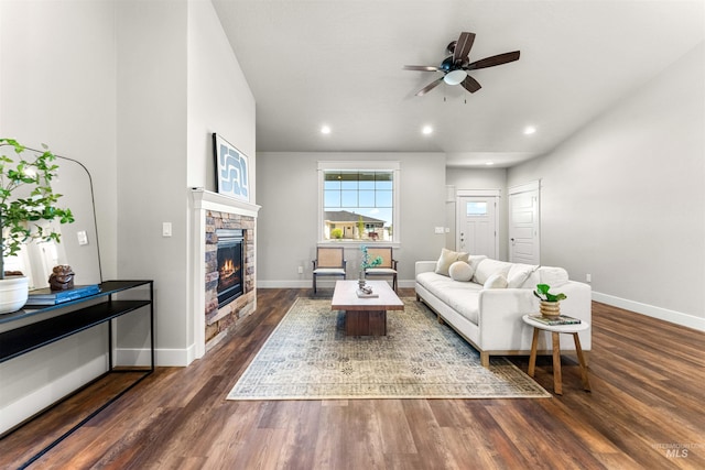 living room with ceiling fan, a stone fireplace, dark wood finished floors, baseboards, and recessed lighting