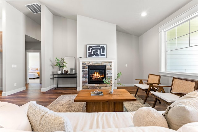 living area featuring a wealth of natural light, a fireplace, dark wood-style flooring, and visible vents