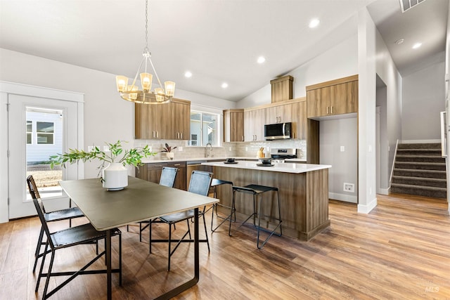 dining room featuring stairs, lofted ceiling, light wood-type flooring, recessed lighting, and a chandelier