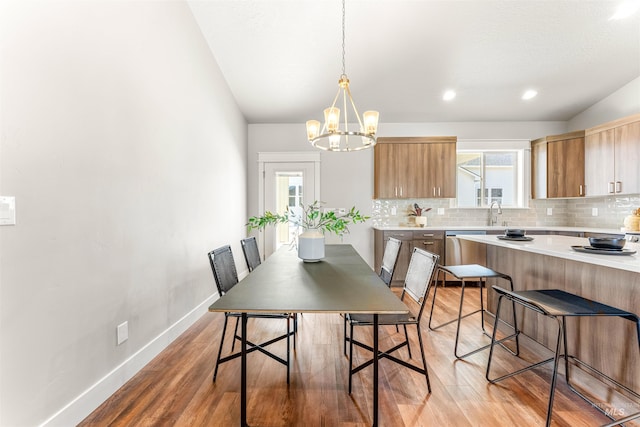 dining space featuring baseboards, light wood-style flooring, a notable chandelier, and a healthy amount of sunlight