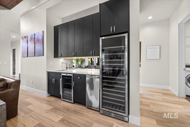 bar featuring light wood-type flooring, wine cooler, washer / dryer, and dishwasher