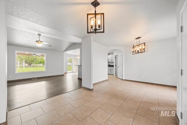 25022 Tumbleweed, Middleton, ID 83644 - unfurnished living room with a chandelier, arched walkways, light tile patterned flooring, a ceiling fan, and baseboards