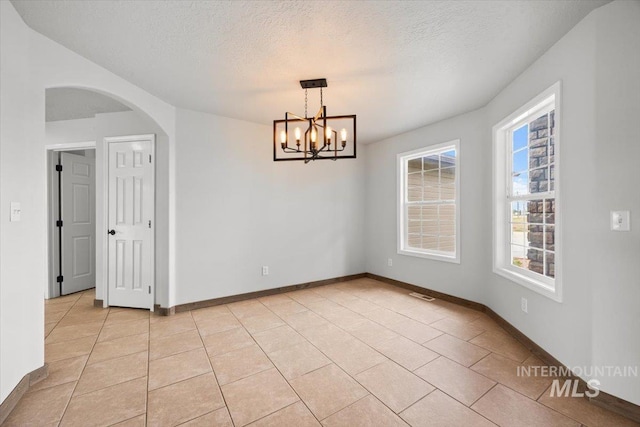25022 Tumbleweed, Middleton, ID 83644 - empty room featuring a textured ceiling, a chandelier, arched walkways, light tile patterned floors, and baseboards