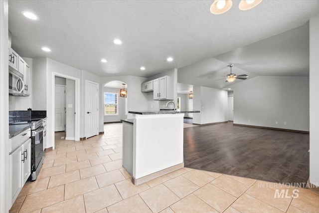 25022 Tumbleweed, Middleton, ID 83644 - kitchen with stainless steel appliances, dark countertops, a peninsula, arched walkways, and ceiling fan