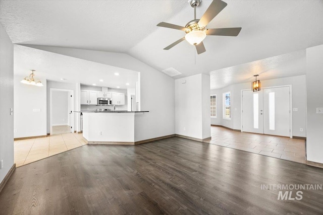 25022 Tumbleweed, Middleton, ID 83644 - unfurnished living room featuring lofted ceiling, wood finished floors, a chandelier, baseboards, and ceiling fan