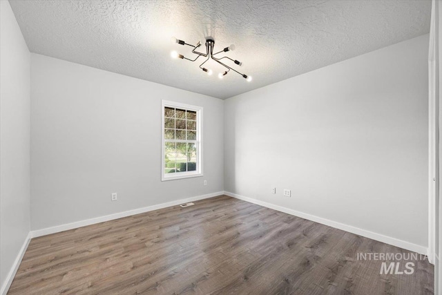 25022 Tumbleweed, Middleton, ID 83644 - unfurnished room featuring a chandelier, wood finished floors, a textured ceiling, and baseboards