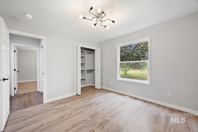 25022 Tumbleweed, Middleton, ID 83644 - unfurnished bedroom with light wood-style flooring, a chandelier, baseboards, a textured ceiling, and a closet
