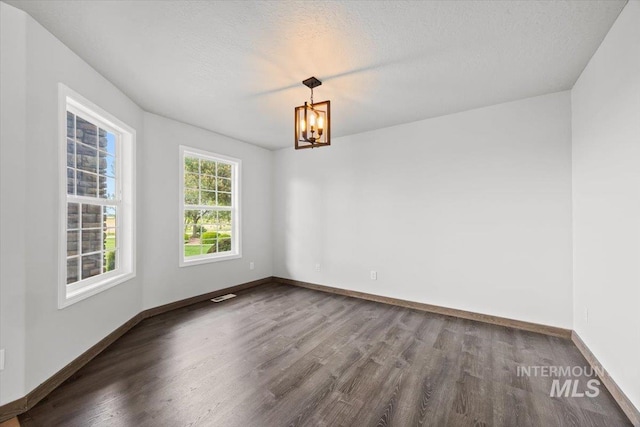 25022 Tumbleweed, Middleton, ID 83644 - empty room with dark wood-style floors, a chandelier, baseboards, and a textured ceiling