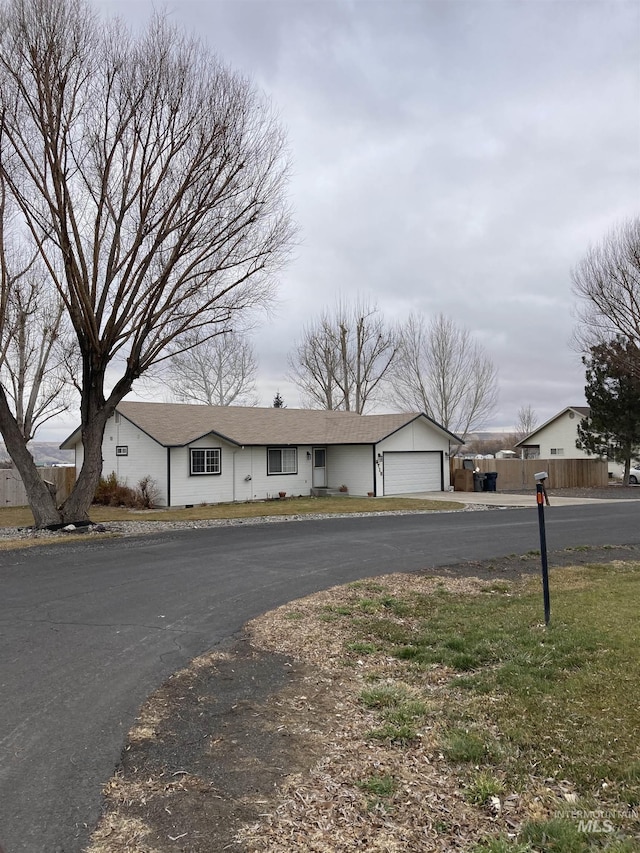 view of front facade with an attached garage, fence, and aphalt driveway