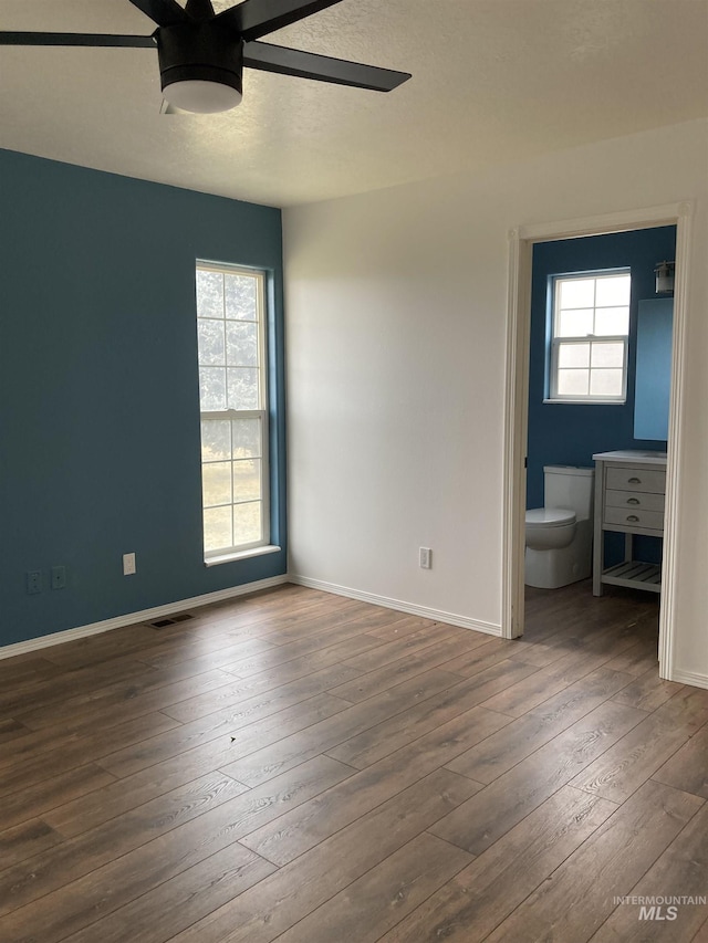 unfurnished bedroom featuring dark wood-style floors, visible vents, baseboards, and a textured ceiling