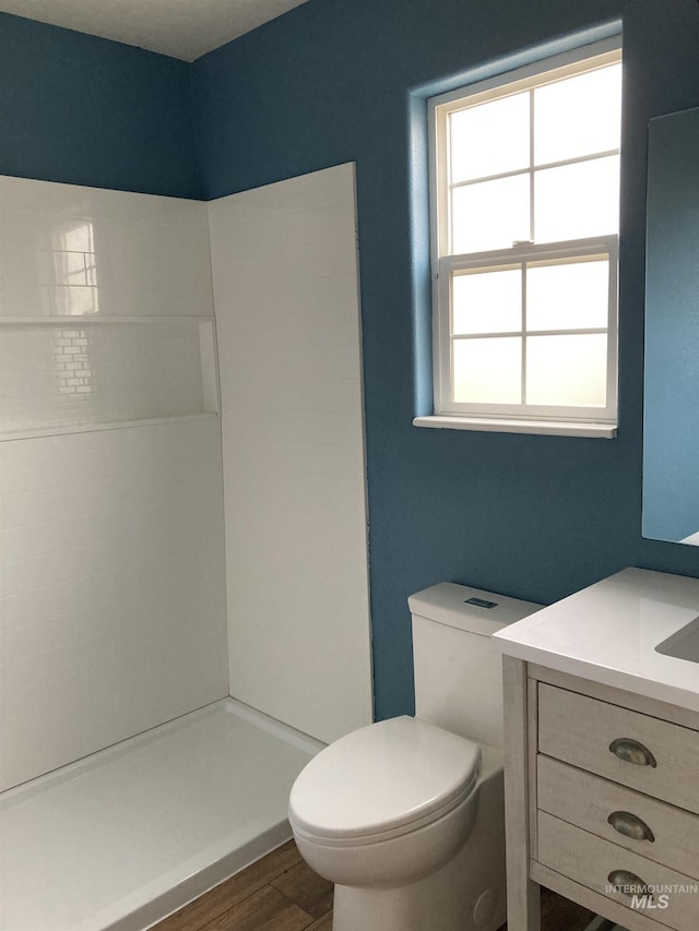 full bath featuring walk in shower, vanity, toilet, and wood finished floors