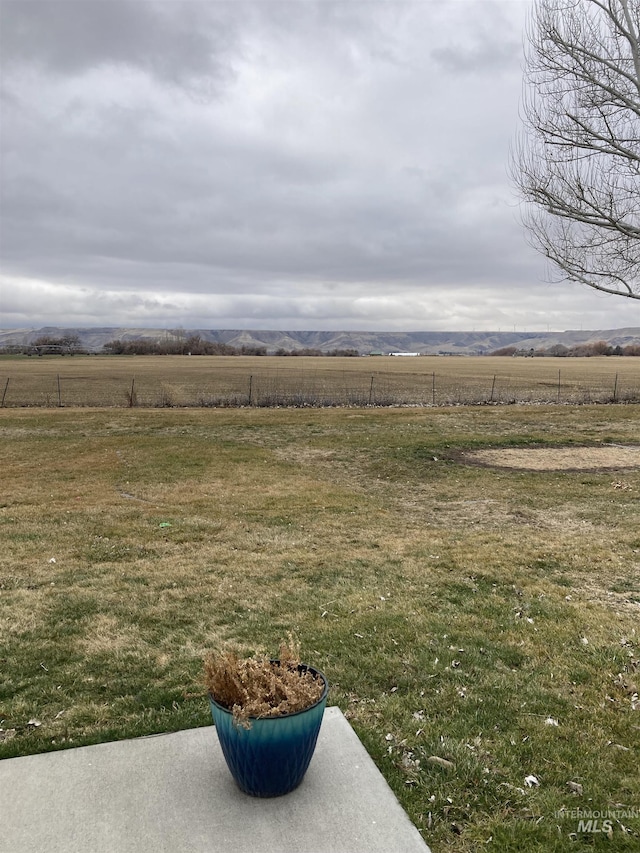 view of yard featuring fence, a mountain view, and a rural view