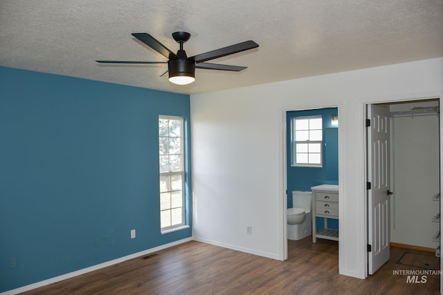 unfurnished bedroom featuring a closet, multiple windows, wood finished floors, and visible vents