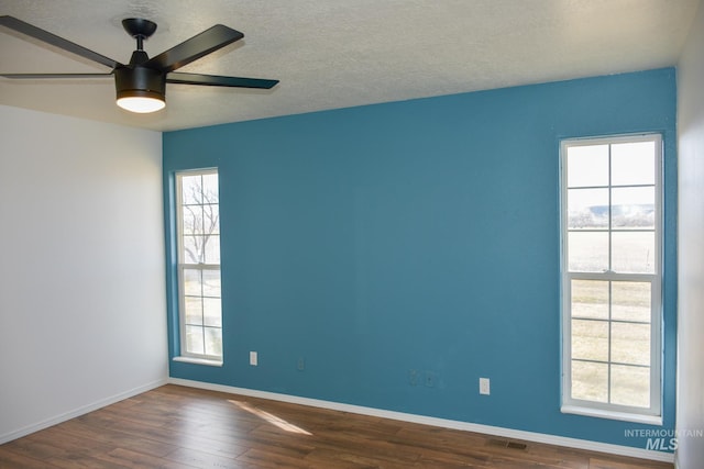 unfurnished room with visible vents, a ceiling fan, a textured ceiling, wood finished floors, and baseboards