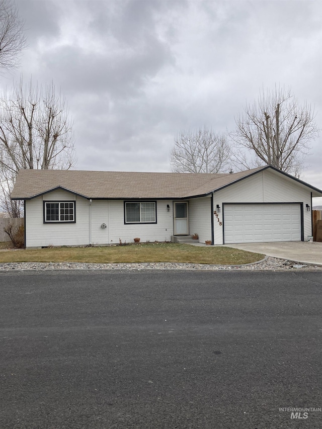 view of front of home with a garage, a front yard, concrete driveway, and a shingled roof