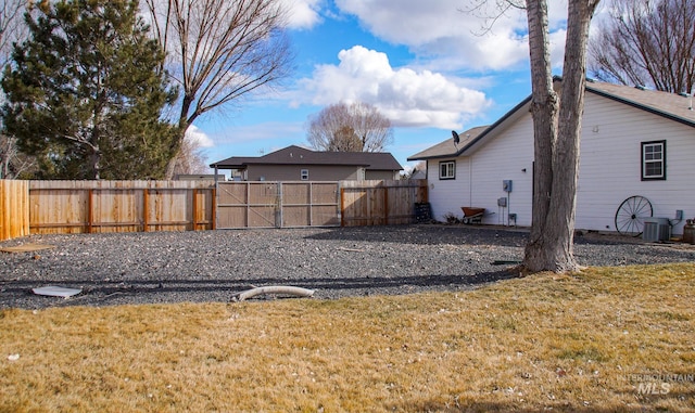 view of yard featuring a gate, fence, and central air condition unit