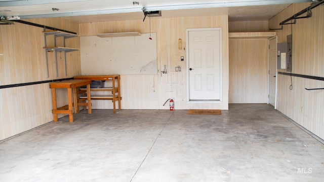 garage with a garage door opener, electric panel, and a workshop area