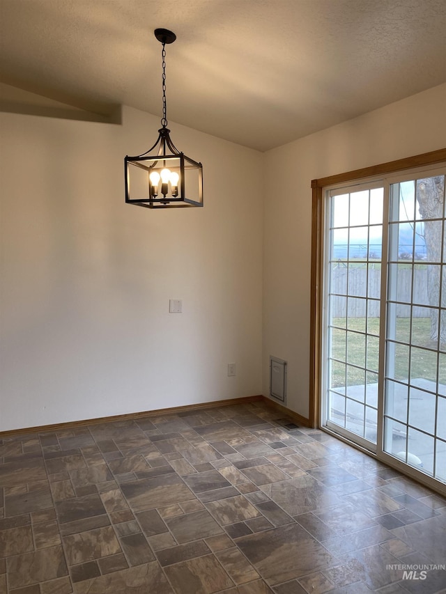 empty room with baseboards, stone finish floor, and an inviting chandelier