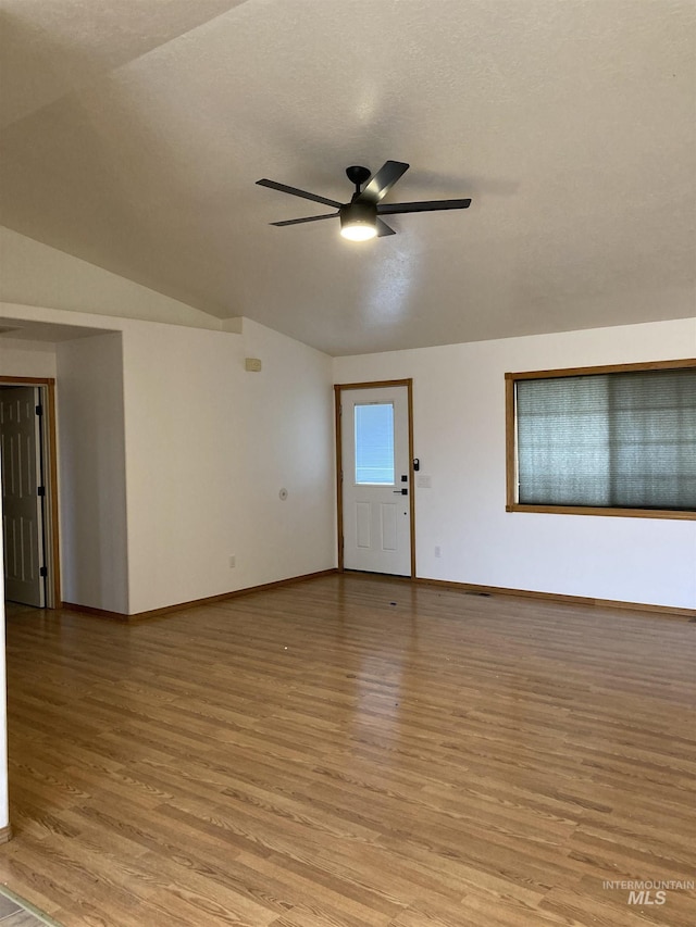 unfurnished room featuring a textured ceiling, a ceiling fan, baseboards, vaulted ceiling, and light wood-style floors