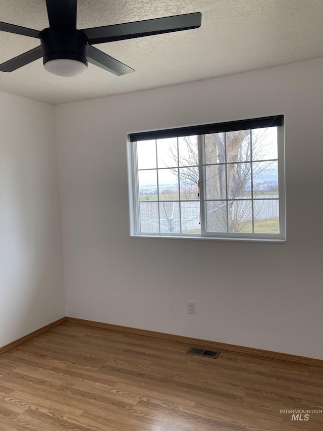 unfurnished room with ceiling fan, baseboards, a wealth of natural light, and wood finished floors