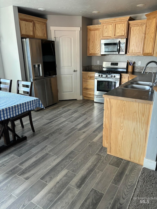 kitchen with appliances with stainless steel finishes, light brown cabinets, sink, and dark hardwood / wood-style flooring