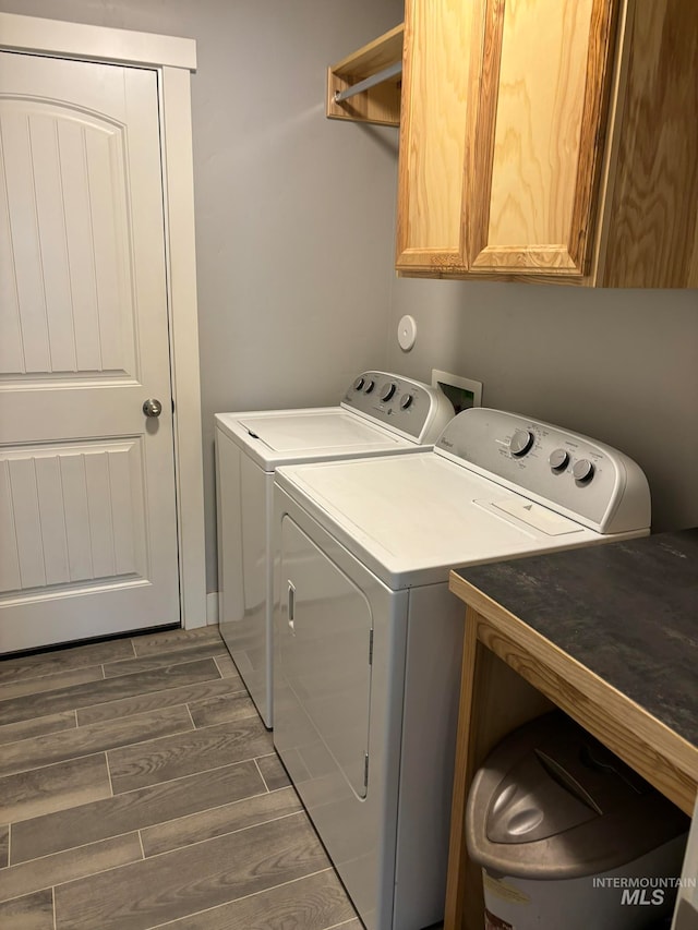 laundry room with dark wood-type flooring, independent washer and dryer, and cabinets