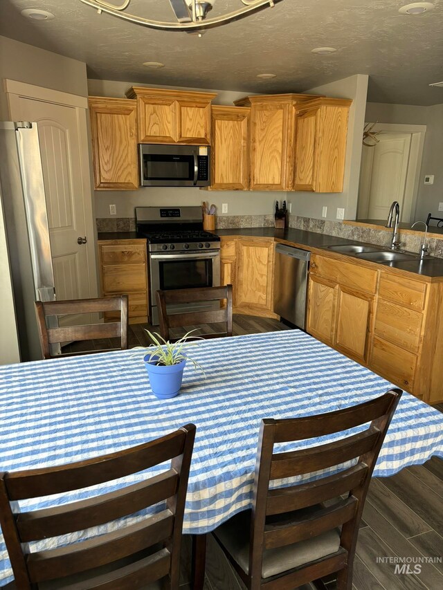 kitchen featuring a textured ceiling, appliances with stainless steel finishes, sink, and dark hardwood / wood-style floors