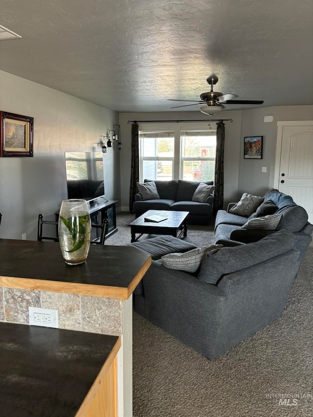 carpeted living room featuring a textured ceiling and ceiling fan