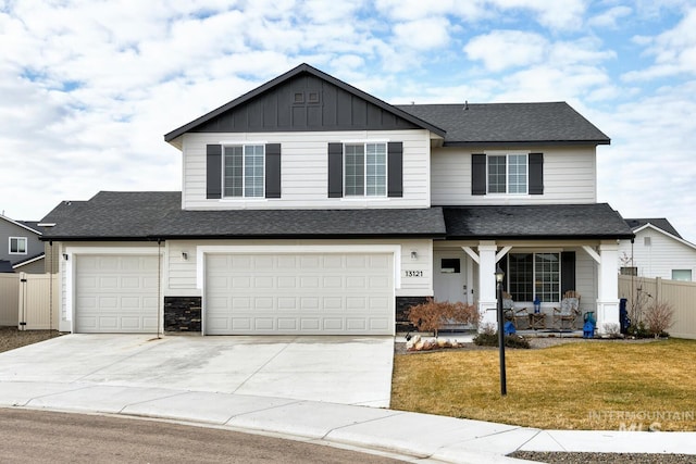 view of front of home with fence, board and batten siding, driveway, a front lawn, and a garage