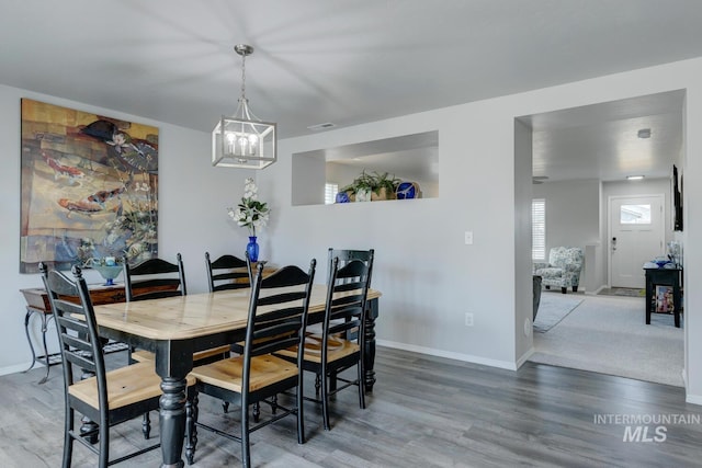 dining room featuring baseboards, visible vents, a notable chandelier, and wood finished floors