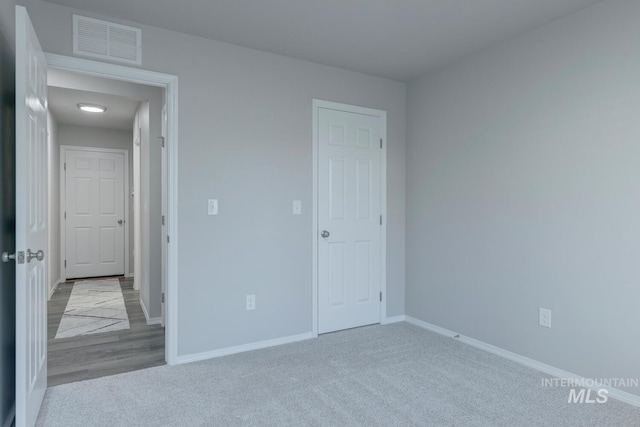 unfurnished bedroom with carpet flooring, baseboards, and visible vents