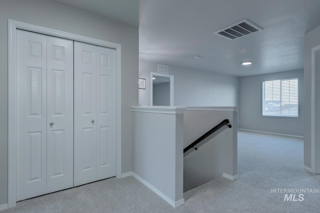 corridor with an upstairs landing, light carpet, and visible vents