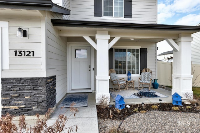 entrance to property featuring covered porch and fence