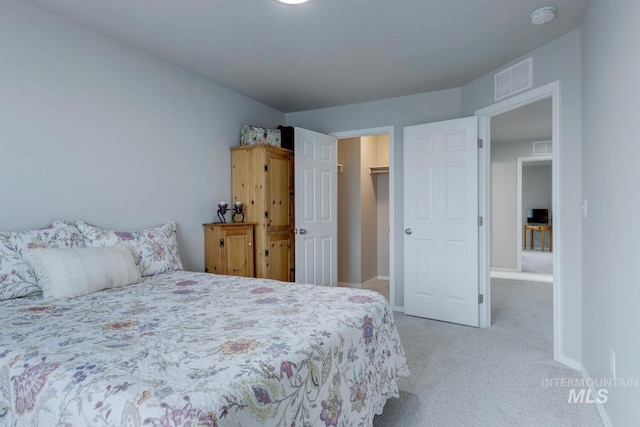 bedroom with baseboards, carpet flooring, visible vents, and a walk in closet