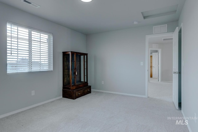 unfurnished bedroom with carpet floors, visible vents, and attic access