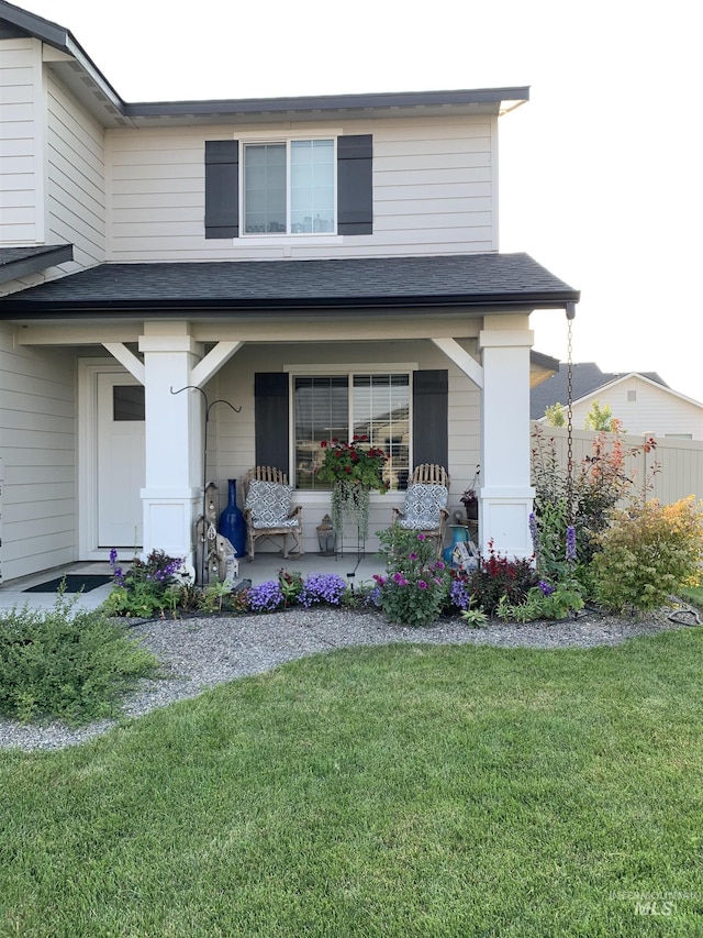 view of front of property with a front lawn, a shingled roof, and a porch