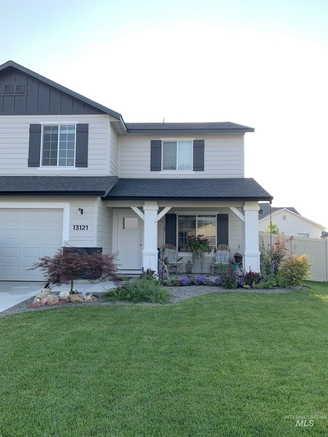 traditional-style home with fence, a front yard, an attached garage, and roof with shingles