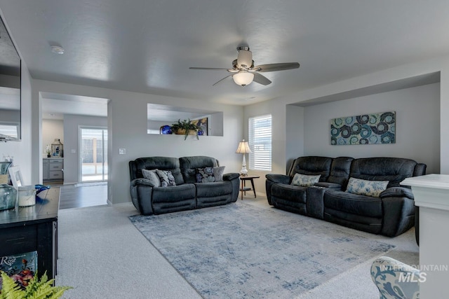carpeted living area with ceiling fan