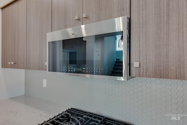 kitchen with decorative backsplash, light brown cabinets, and light stone counters