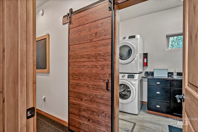 washroom with a barn door and stacked washer / dryer