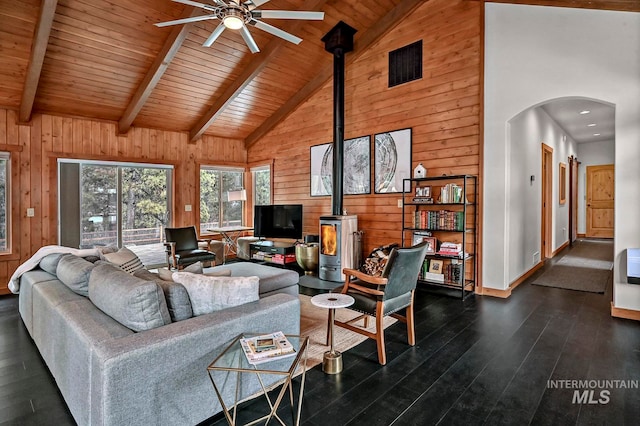 living room featuring a wood stove, wooden walls, and high vaulted ceiling