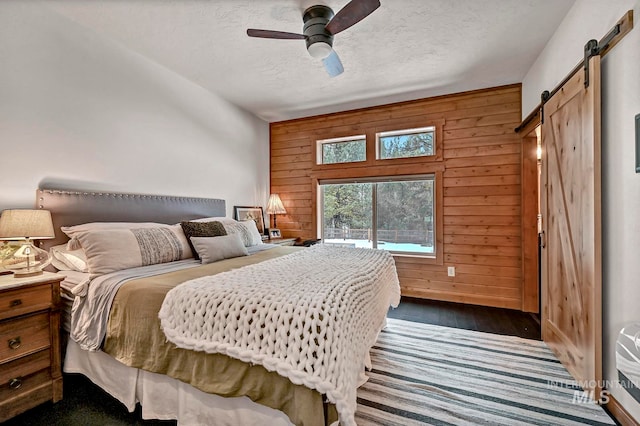 bedroom with a textured ceiling, ceiling fan, and wood walls