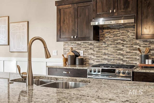 kitchen featuring light stone counters, high end stainless steel range, dark brown cabinets, and sink