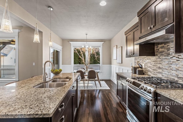 kitchen featuring appliances with stainless steel finishes, light stone counters, sink, dark hardwood / wood-style floors, and an island with sink