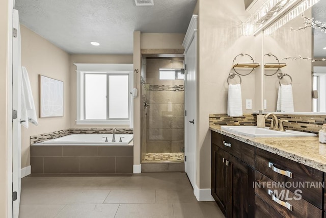 bathroom featuring plus walk in shower, tile patterned flooring, vanity, and a healthy amount of sunlight